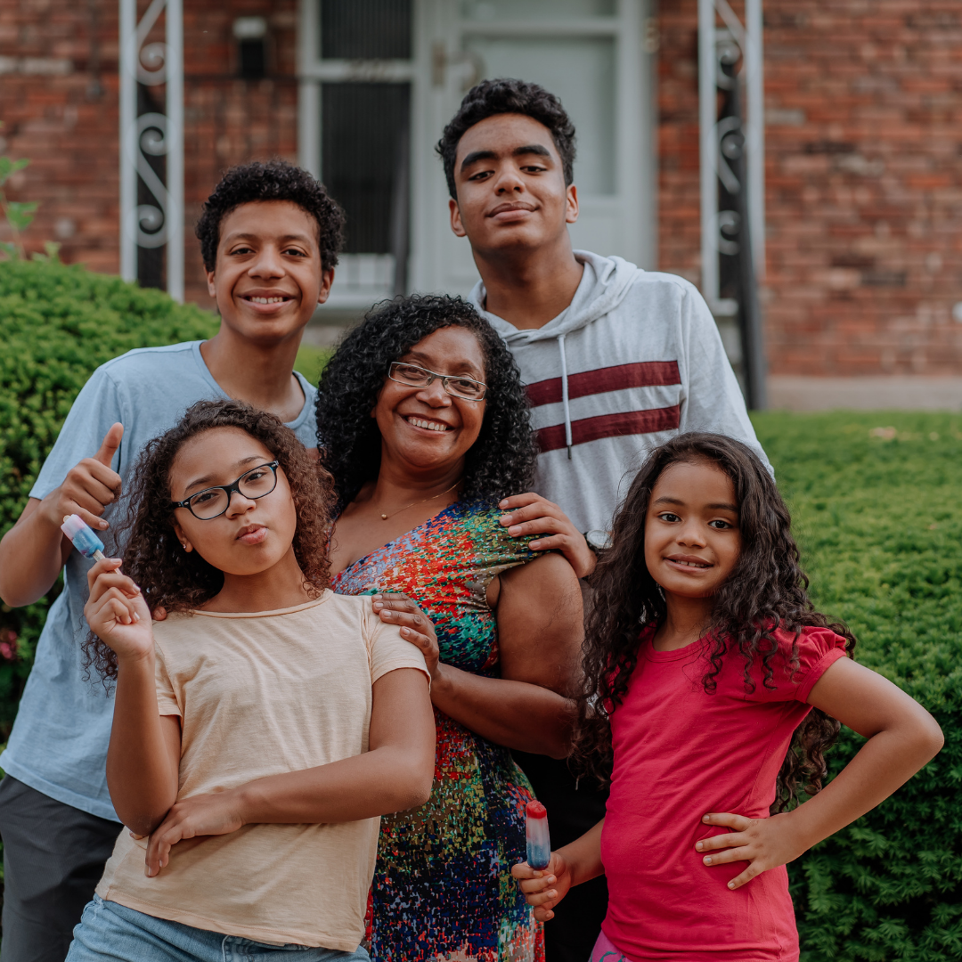 Mother and 4 children smiling outside a house