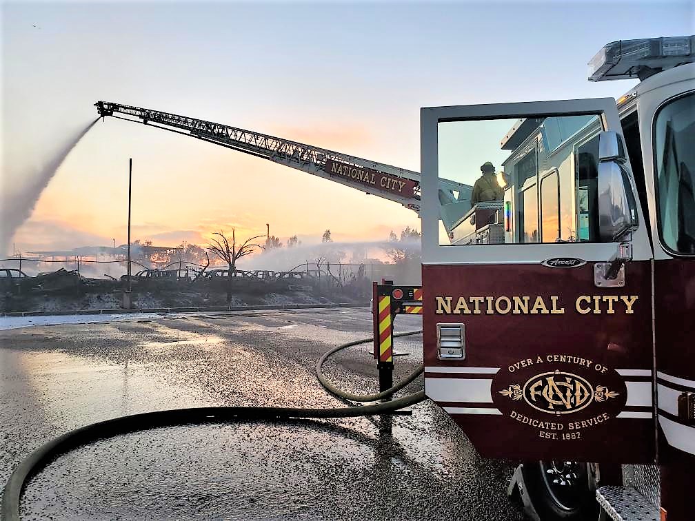 NCFD truck fighting a fire and spraying water on the fire from the truck ladder